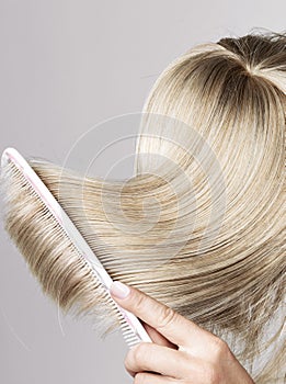 Blond hairpiece brushed by a woman