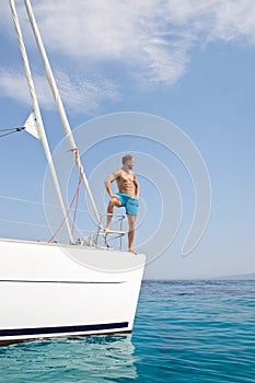 Blond handsome young man posing on sailing boat.