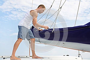 Blond handsome young man on sailing boat.