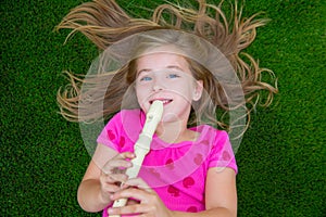 Blond kid children girl playing flute lying on grass