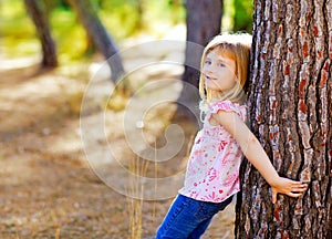 Blond kid girl on autumn tree trunk