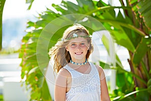 Blond kid girl at banana tree leaves in bright day