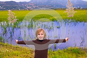 Blond kid girl outdoor holding spike in wetlands lake