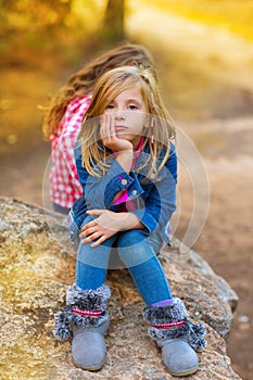 Blond kid girl pensive bored in the forest outdoor