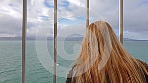 Blond Lady holding the bars and looking to sea and land