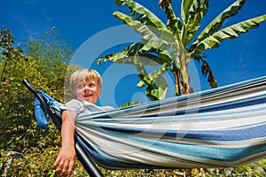 Blond little boy rest in hammock at the garden