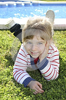 Blond little girl laying on pool grass posing