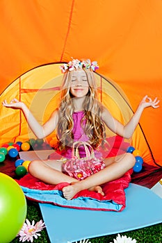 Blond little girl practicing yoga in camping tent