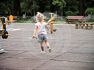 Blond little girl running in the playground