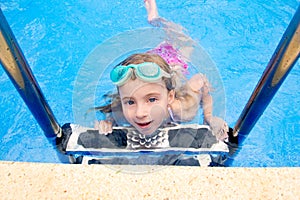 Blond little girl in swimming pool with goggles