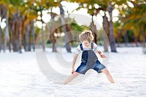 Blond little kid boy having fun on Miami beach, Key Biscayne. Happy healthy cute child playing with sand and running