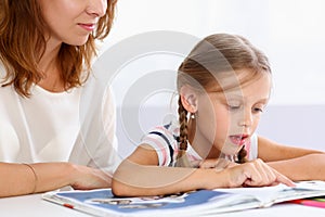 Blond little reading together with mom