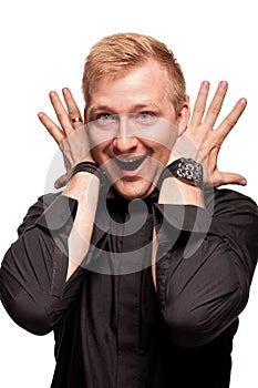 Young blond man in a black shirt, watches and bracelet is making faces, isolated on a white background