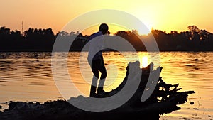 Blond man climbs the tree roots on a lake bank in slo-mo