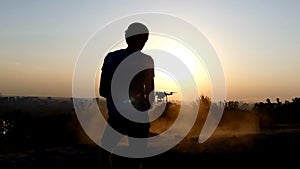 Blond man controls the flight of a drone at a nice sunset