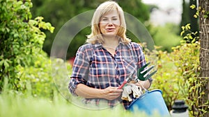 blond mature woman holding horticultural tools