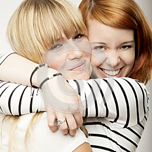 blond and red haired girl friends laughing and hug
