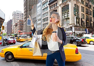 Blond shopping tourist girl calling a yellow Taxi NYC