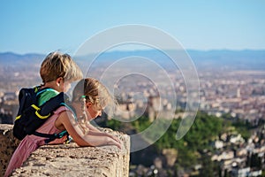 Blond siblings stand on viewpoint admire Alhambra castle