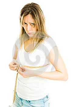 Blond slim woman in white shirt and jeans measure chest size with tape meter - not happy