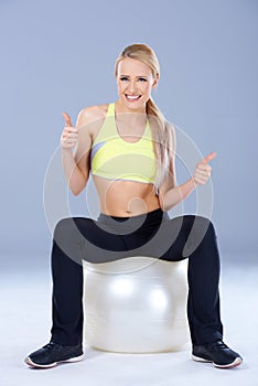 Blond sporty woman sitting on fitness ball