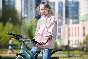 Blond teenage girl sitting on her blue bicycle, portrait outdoor