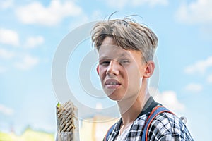 Blond teenager enjoying chicken shawarma in park on summer day