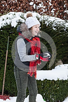 Blond teenager girl making a snowball in snowy back yard