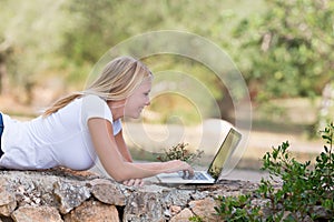 Blond teenager using laptop outdoor