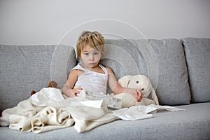 Blond toddler child, wiping his nose in a tissue, sneezing and coughing