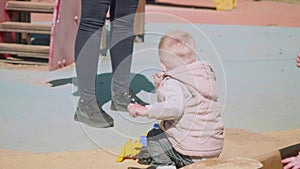 Blond toddler plays with toy tractor on playground