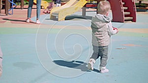 Blond toddler walks on playground