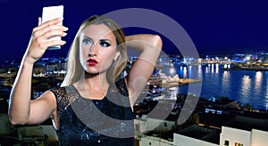Blond tourist girl taking selfie photo in Ibiza skyline