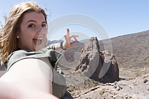 Blond Tourist taking selfie in Tenerife in the national park of el Teide in Llano de Ucanca with a big rock and arid, volcanic