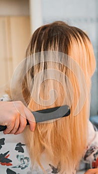 blond woman in the bathroom straightens her hair with a curling iron