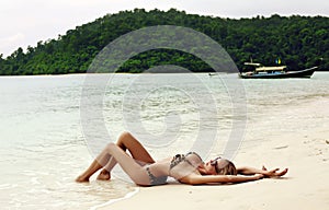 blond woman in bikini relaxing on beach in Thailand