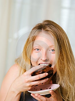 Blond woman biting a chocolate brownie photo
