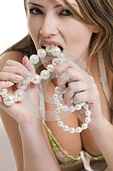 Blond woman biting a pearl necklace