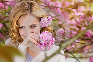 Blond woman, curly hair against pink tree in blossoom photo