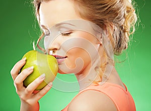 Blond woman eat green apple over green background