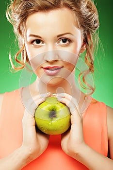 Blond woman eat green apple over green background