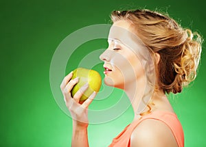 Blond woman eat green apple over green background