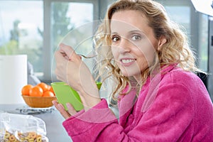 Blond woman eating cereals, at morning