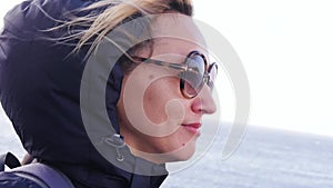 A blond woman with glasses is sailing on a steamboat. Tourist, mother, walk on water with family, sea, river, profile