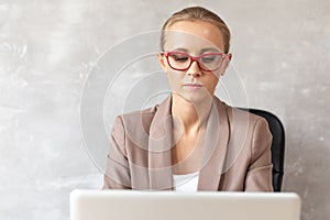 Blond woman in glasses working with lapatop. Office worker
