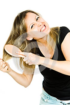 Blond woman having problem with brushing long straight tangled hair with hairbrush - hopeless situation