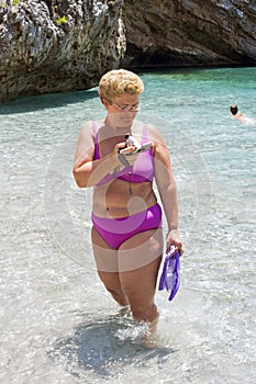 Blond woman with her son at the beach bathing in crystalline water.