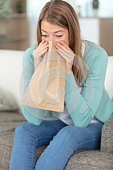 blond woman holding brown paper bag over mouth