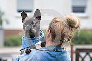 Blond woman holding French Bulldog dog over shoulder