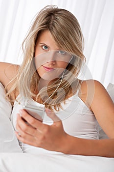 Blond woman holding mp3 player listening to music